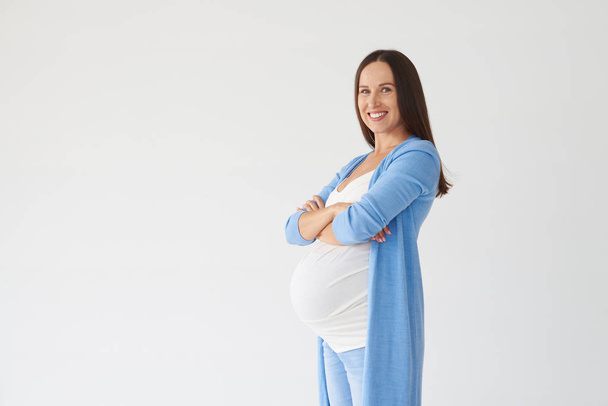 Pregnant woman folded hands against white background - Foto, afbeelding