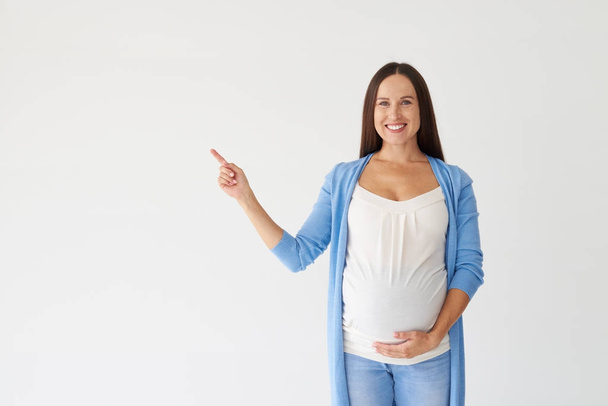 Jonge zwangere vrouw wijzend op kopie ruimte  - Foto, afbeelding