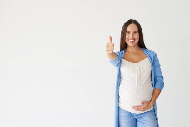Vrij lachende zwangere vrouw weergegeven: duimschroef opwaarts gebaar  - Foto, afbeelding