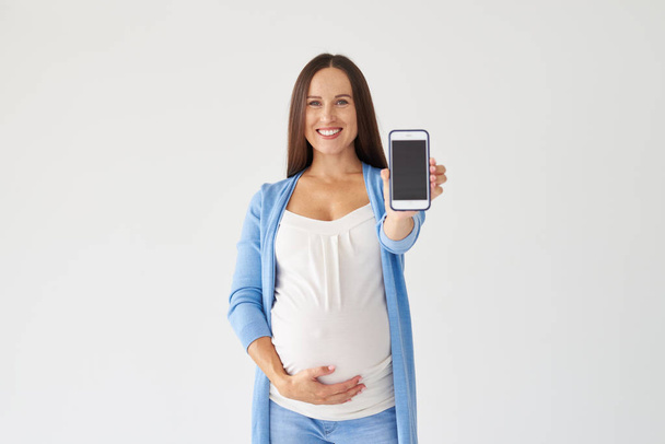 妊娠中の女性が携帯電話のディスプレイ - 写真・画像