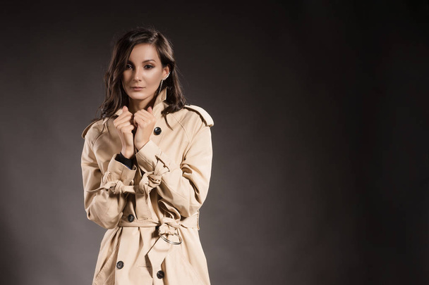 The brunette girl in a raincoat on a gray background - Photo, image