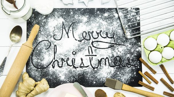 Feliz Natal. escrito em uma placa preta polvilhada com farinha. Conceito de cozinha de Natal
 - Foto, Imagem