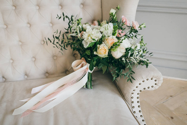 Bouquet da sposa rustico con rose cremose e garofani bianchi su un divano crema di lusso. Primo piano. Vista laterale
 - Foto, immagini