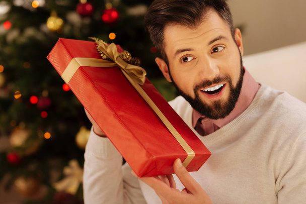 Uomo sorridente che vuole conoscere le interiora della confezione regalo
 - Foto, immagini