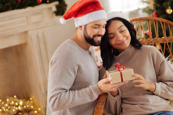 Happy woman cuddling husband giving her Christmas present - Foto, afbeelding