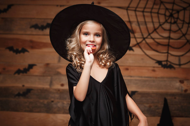 Halloween cadı kavramı - küçük cadı Cadılar Bayramı tatlı çocukla ve neşeli gülümseyen şeker. yarasa ve örümcek web arka plan üzerinde. - Fotoğraf, Görsel