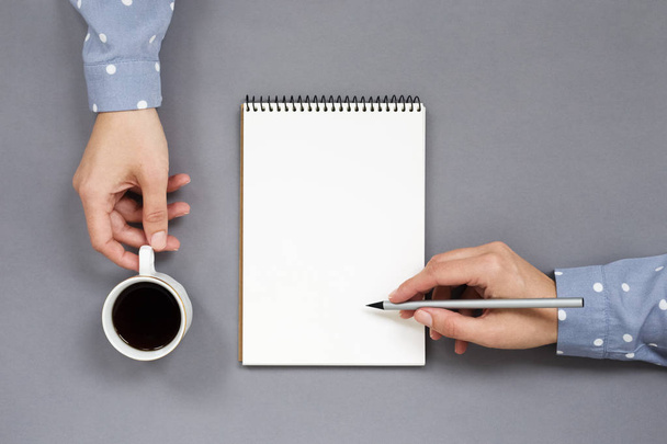 Vrouw handen, schrijven en houden op grijze minimale werkplek  - Foto, afbeelding