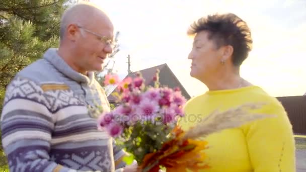 Idoso homem está dando flores para sua senhora e eles estão se beijando ao pôr do sol
 - Filmagem, Vídeo
