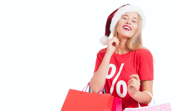  happy young woman with santa hat carrying shopping bags - Fotó, kép