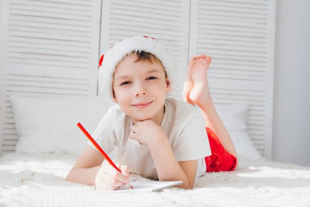 Boy in a red cap writes a letter to Santa - Valokuva, kuva