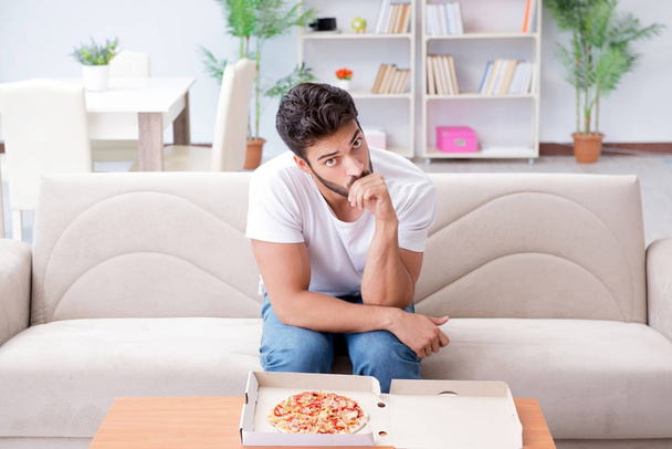 Pizza yiyen adam evde yemek yiyor, dinleniyor. - Fotoğraf, Görsel