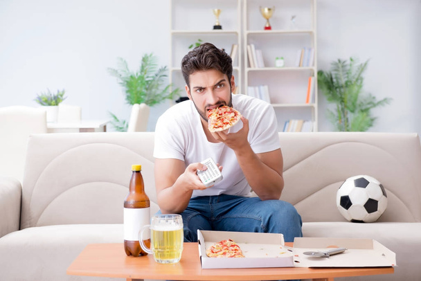 Hombre comiendo pizza teniendo una comida para llevar en casa descansando relajado - Foto, imagen