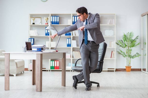 Επιχειρηματίας έχει τη διασκέδαση κάνοντας ένα διάλειμμα στο γραφείο στη δουλειά - Φωτογραφία, εικόνα