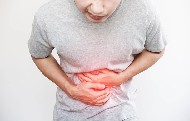 a man pressing his stomach, with red highlight of stomach pain and others stomach disease concept, on white background with copy space - Photo, Image