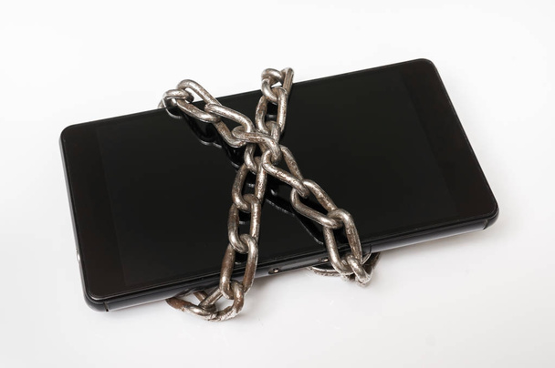 Mobile phone with metal chain locked on white - Photo, Image