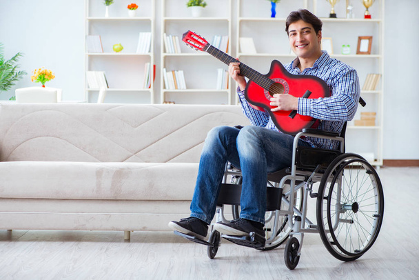 Zdravotně postižený muž hraje doma na kytaru - Fotografie, Obrázek