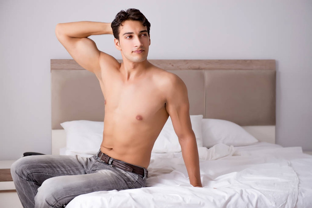 Young handsome shirtless guy showing nude torso sexy on bed at h - Fotoğraf, Görsel