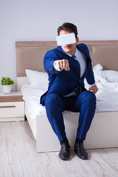 Бизнесмен в гарнитуре виртуальной реальности в спальне - Фото, изображение