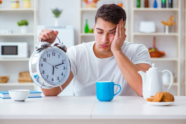 Человек с будильником засыпает за завтраком - Фото, изображение