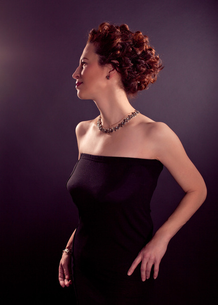 Elegant bosomy mature woman in black tight dress and red curly hair - Foto, imagen