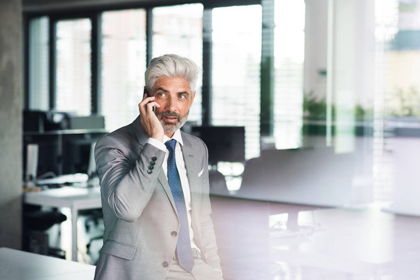 Mature businessman with smartphone in the office. - Photo, Image