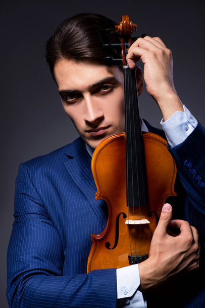 Mladý muž hraje na housle v tmavé místnosti - Fotografie, Obrázek