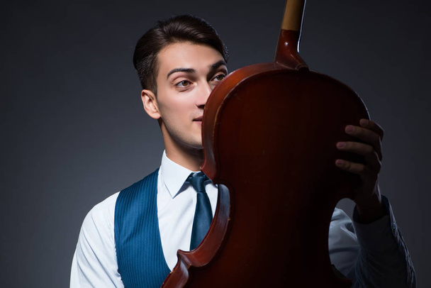 Jeune homme jouant du violoncelle dans la chambre noire - Photo, image