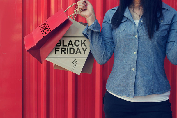 Mujer sosteniendo el Viernes Negro bolsas de compras mientras está de pie en rojo me
 - Foto, imagen