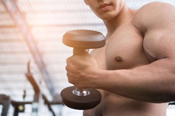 man lift dumbbell in gym. bodybuilder male working out in fitnes - Photo, Image