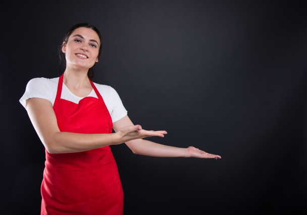 Happy female with red apron invinting you in - Fotoğraf, Görsel