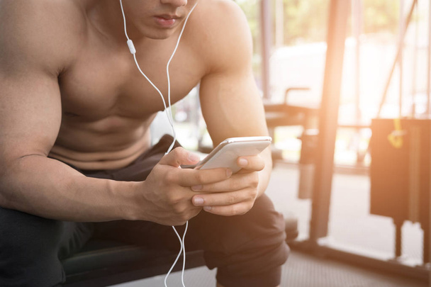 young man use mobile phone in fitness center. male athlete liste - Fotoğraf, Görsel