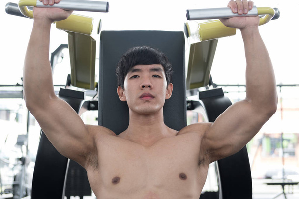 young man execute exercise with weightlifting machine in fitness - Photo, Image