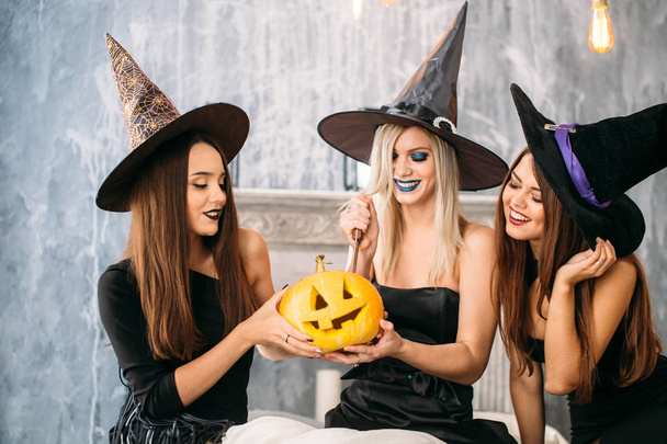 Three adult women carve Halloween pumpkins while laughing and having a party - Fotoğraf, Görsel