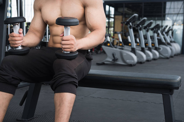 man lift dumbbell in gym. bodybuilder male working out in fitnes - Фото, зображення