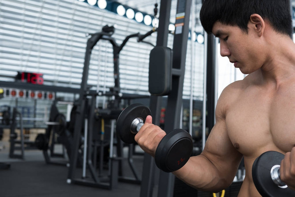 man lift dumbbell in gym. bodybuilder male working out in fitnes - Foto, Imagem
