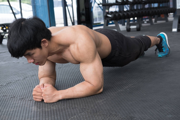άνθρωπος μυών που κάνουν σανίδα θέση στο γυμναστήριο. bodybuilder αρσενικό εργασίας - Φωτογραφία, εικόνα