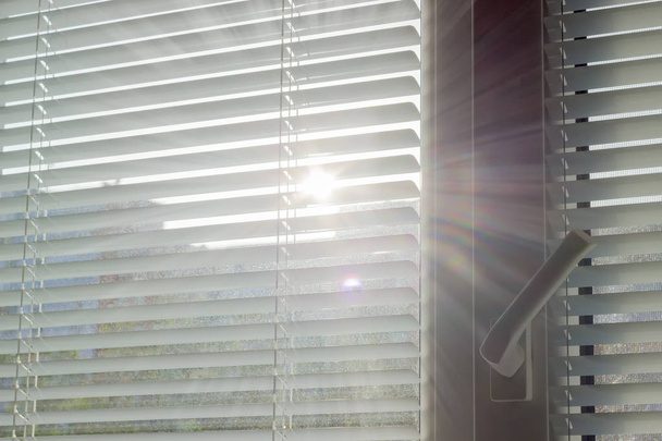 Zonnestralen maken hun weg via de blinds - Foto, afbeelding