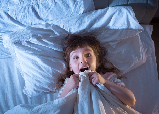 The girl is terrified lying in bed - 写真・画像