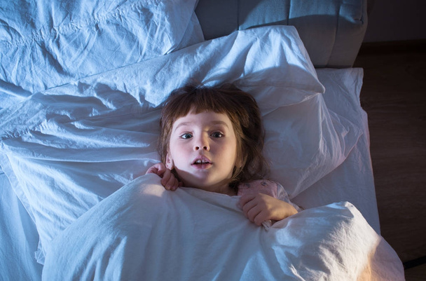 A girl of 4 years is afraid of lying in bed - 写真・画像