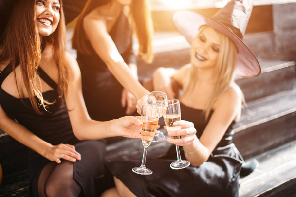 Three girls sit and clink glasses with champagne - Foto, Imagen