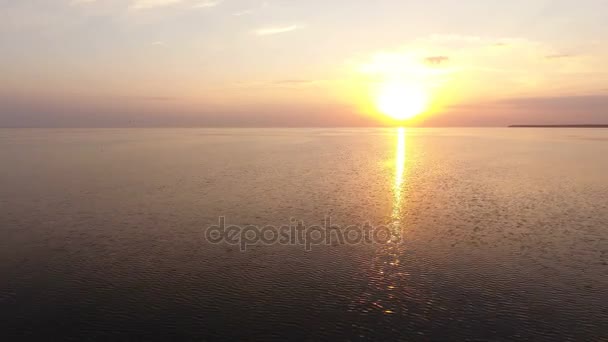 Luchtfoto van een prachtige zonsondergang over het glinsterende water van de zee op een zonnige dag in de zomer - Video