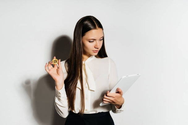 beautiful girl with a gold coin looks into the documents. Crypto currency, bitcoins. - Foto, afbeelding