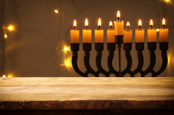 Empty wooden table in front of jewish holiday Hanukkah background with menorah (traditional candelabra) - Foto, immagini