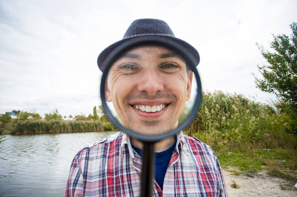 Веселий чоловік зі смішним обличчям тримає збільшувальний келих
 - Фото, зображення