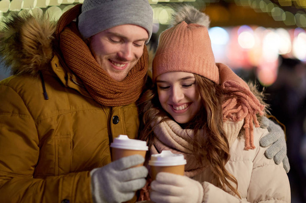 happy couple with coffee over christmas lights - Fotoğraf, Görsel