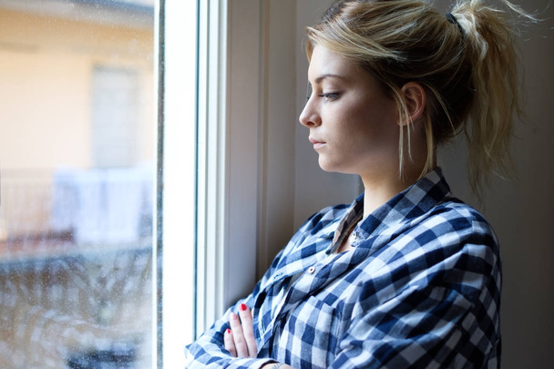 Беспокойная и одинокая девушка рядом с окном
 - Фото, изображение