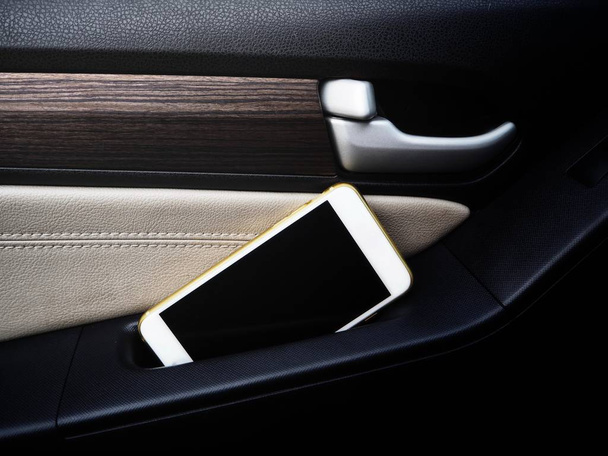 γκρο πλαν θέα του smartphone με κενή οθόνη και αυτοκίνητο πόρτα  - Φωτογραφία, εικόνα