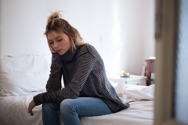Smutny młoda kobieta zmęczona, siedząc na łóżku - Zdjęcie, obraz