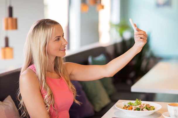 woman with smartphone taking selfie at restaurant - Foto, Bild