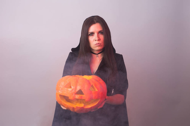 Halloween witch holding a orange pumpkin Jack o Lantern with smoke - Foto, Imagem